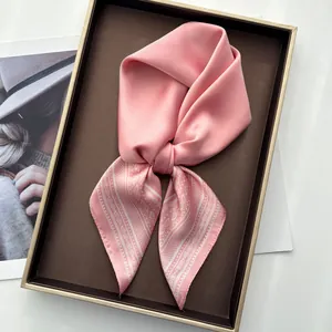 Pink satin square scarf with white paisley pattern displayed on an elegant tray