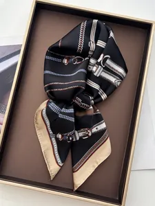 Detailed view of silk scarf with chain pattern on a tray showcasing smooth satin texture