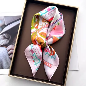 Detailaufnahme eines Seidentuchs mit Fruchtprint in Geschenkbox neben Modemagazin