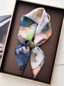 Detailed view of abstract ink-style silk twilly scarf tied in a luxury gift box