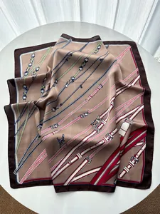 Detail view of silk square scarf featuring chain and belt prints on a white table