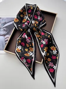 Détail d'un foulard en satin à fleurs noué en boucle sur un plateau de présentation