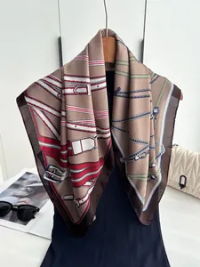 Close-up of silk square scarf with chain and belt patterns on a wooden hanger
