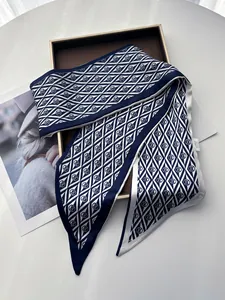Detail of 100% mulberry silk twilly scarf with geometric logo patterns on a display tray
