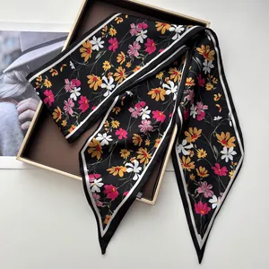 Détail du motif floral sur foulard en satin noir avec imprimé de marguerites roses