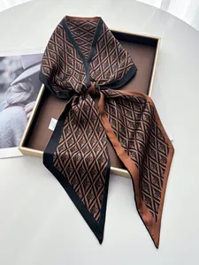 Detail of elegant satin scarf with vintage monogram print and pointed ends in a gift box