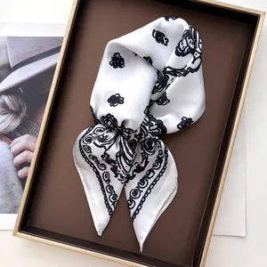 Detail of silk square scarf featuring black rose patterns in a gift box with magazine