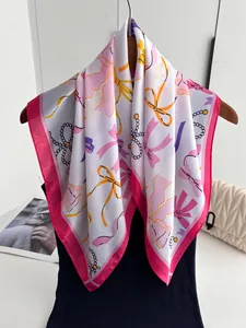 Detail eines Seidenschals mit rosa Schleifenmuster an einem Holzkleiderbügel aufgehängt