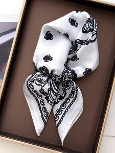 Detail of silk-like square scarf with black floral print on white fabric in a brown tray