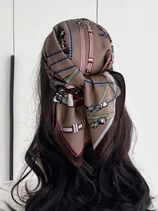 Detail of silk square scarf tied as a headband featuring equestrian chain and belt motifs
