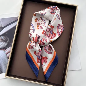 Detail of silk-like scarf with pink rocking horse print and colorful border in a tray