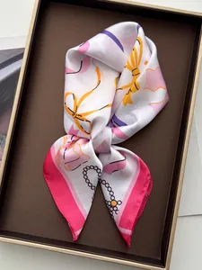 Nahaufnahme von Seidenschal mit orangefarbenen Schleifen und rosa Blumen auf einem Tablett