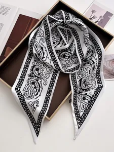 Nahaufnahme eines Satin-Schals mit Paisleymuster in Schwarz-Weiß auf einem Tablett