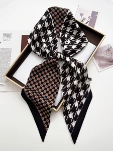 Detail of houndstooth and plaid patchwork silk scarf tied in a bow on a decorative tray