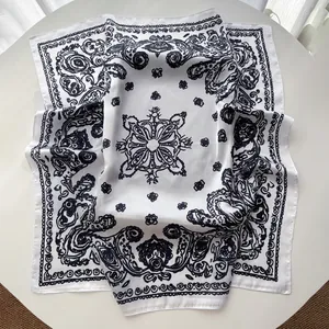 Detail of silk-like square scarf featuring baroque paisley patterns on white fabric