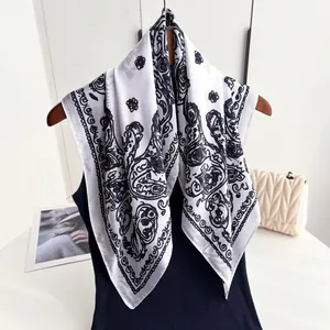 Detailed view of white silk scarf with baroque floral patterns hanging on a wooden hanger