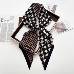 Detail of long satin twilly scarf with houndstooth and check patterns on magazine