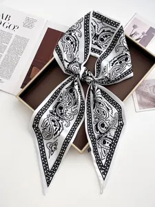 Detail eines eleganten schwarz-weißen Paisley-Seidenschals auf einem Luxustablett