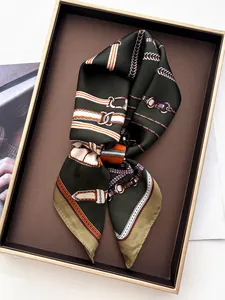 Detailed close-up of a silk scarf with classic chain and buckle patterns in a display box