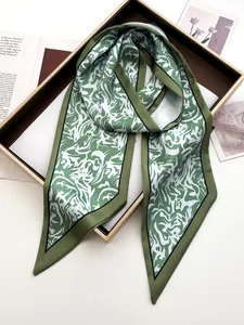 Détail d'un foulard twilly en satin de soie avec motif marbré vert et blanc en coffret