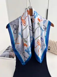 Detail eines Seidengefühl-Schals mit bunten Schleifenprints und eleganten Perlenmustern