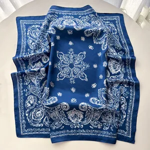 Detailed view of dark blue silk scarf with white paisley patterns on marble background
