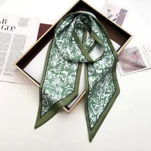 Détail d'un élégant foulard en satin vert avec motifs abstraits dans un coffret cadeau
