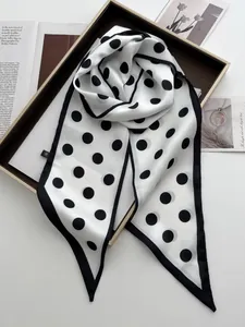 Detailed macro view of the black and white polka dot silk satin scarf texture and edge