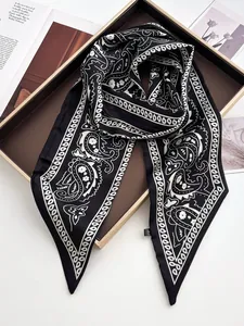 Detail eines eleganten schwarzen Paisley-Seidenschals mit weißem Muster auf Tablett