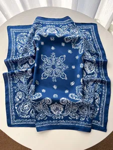 Detailed close-up of navy blue silk-like square scarf with white paisley pattern motifs