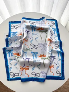 Makroaufnahme von Seidenschal mit bunten Schleifenprints und blauem Saum auf dem Tisch