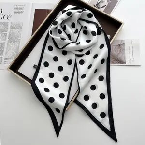Detail of black and white polka dot satin scarf on wood tray with fashion magazine