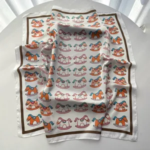 Close-up of square silk scarf featuring colorful rocking horse prints and satin texture