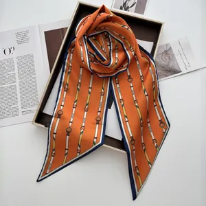 Dettaglio di un foulard in seta arancione con stampa a catena e bordo blu navy