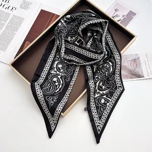 Detailansicht eines Seidenschals mit Paisley-Muster und Ketten auf einem Goldtablett