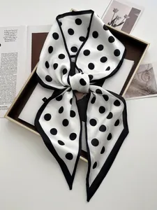 Close-up of a stylish black and white polka dot silk scarf tied in an elegant bow knot
