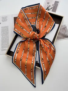 Dettaglio foulard in seta arancione con stampa equestre in confezione regalo