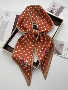 Detail eines Retro-Seidenband-Schals in Orange mit weißen Punkten und Blumen-Prints