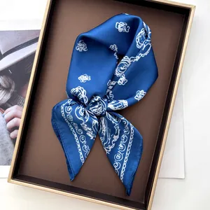 Detailed view of navy blue silk scarf with white floral patterns on a display tray