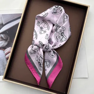 Close-up of pink silk scarf with rocking horse print folded in a gold frame tray