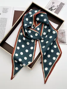 Detailed view of dark green polka dot silk scarf draped over a brown display tray