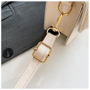 Detail of high-gloss gold hardware and adjustable leather strap on linen texture bag