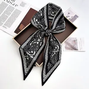 Detail eines Seidensatin-Schals mit schwarz-weißen Paisley-Mustern als Schleife gebunden