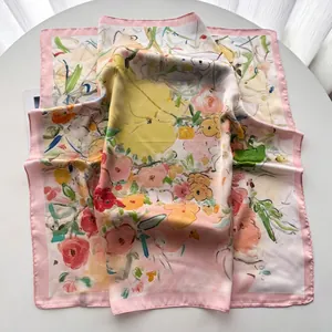 Détail d'un foulard carré en satin de soie avec imprimé floral et bordure rose