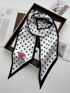 Nahaufnahme von elegantem Seidenschal mit Punkten und Lotusblumen-Druck im Tablett