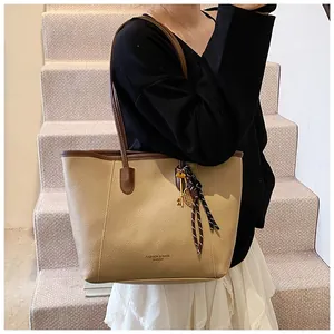 Detalle del bolso tote grande con ribete en contraste y accesorio de raqueta de tenis