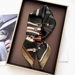 Green silk square scarf with chain belt print displayed on a brown metal tray