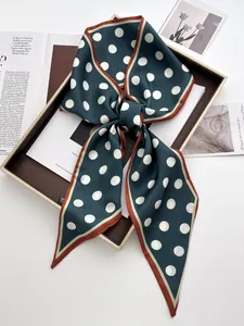 Detailed view of dark green polka dot silk scarf tied in a bow inside a gift box
