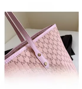 Close-up of pink tote bag showing the M-pattern print and metallic gold rivet details