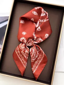 Close-up of wine red faux silk scarf with white rose and paisley print in a gift box